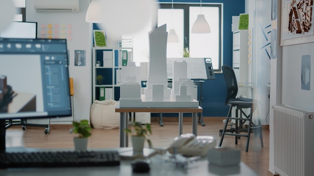 Niemand op kantoor met 3D-architectuurontwerp en bouwmodel voor stedelijk project. Lege ruimte met bouwprint en blauwdrukkenplannen voor vastgoedontwikkeling en schetstechnologie.