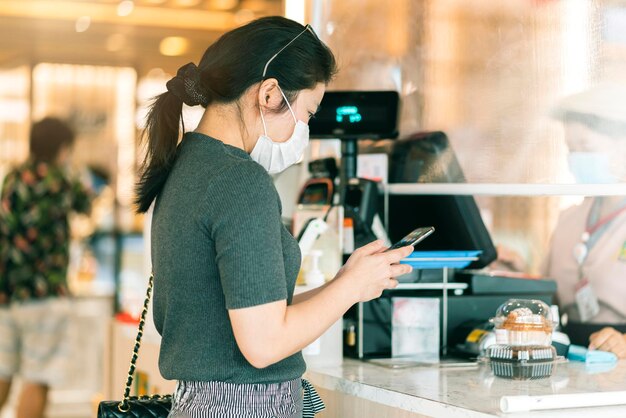 Nieuw normaal na covid-epidemie aziatische vrouwelijke betalingsvoortgang koop scan-app door smarthine cashless en touchless nieuwe levensstijl winkelen in de kassierbalie van het warenhuis