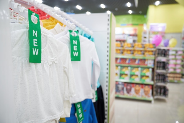 Nieuwe witte kinderkleren die in grote opslag hangen