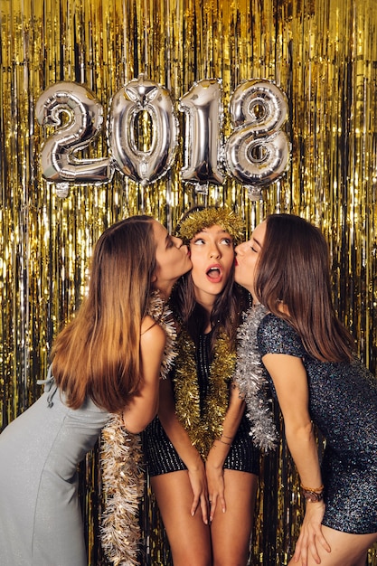 Gratis foto nieuwjaar feest met twee meisjes zoenen vriend