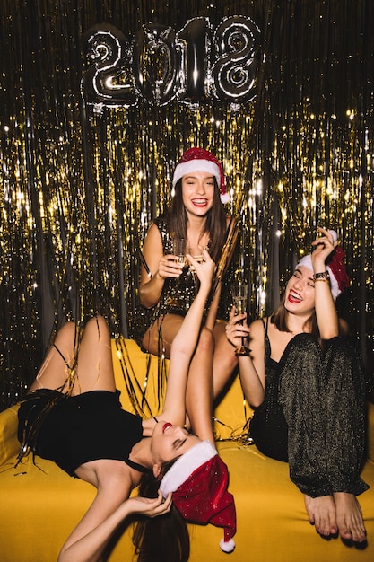 Gratis foto nieuwjaar feestje met drie meiden met plezier op de bank