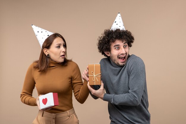 Nieuwjaar fotograferen met een jong koppel draagt een nieuwjaarshoed emotioneel meisje met hart en lachende man