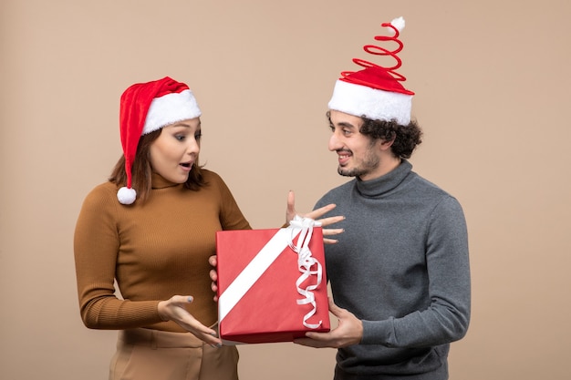 Nieuwjaarsstemming met grappig mooi paar dat rode hoeden van de Kerstman op grijs voorraadbeeld draagt