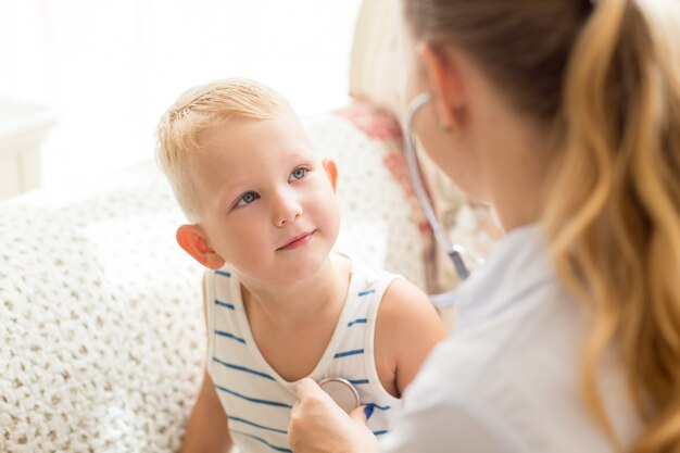 Nieuwsgierig kleine jongen die vrouwelijke arts bekijkt