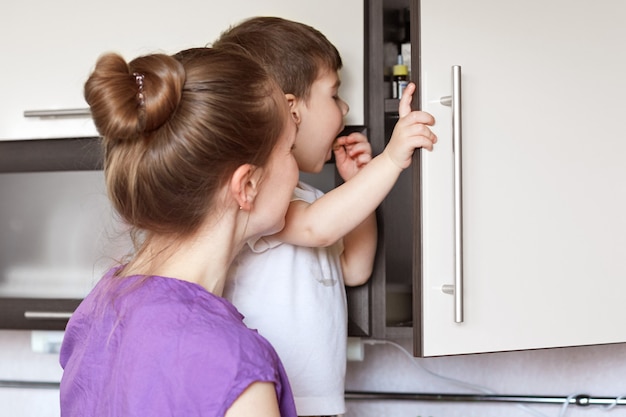 Nieuwsgierige kleine jongen kijkt met grote interesse in keukenplank