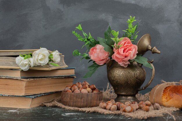Noten met boeken en vaas met bloemen op marmeren tafel.