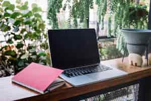Gratis foto notitieboekje dichtbij laptop in tuin