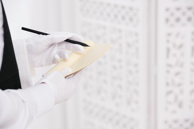 Ober met handschoenen schrijven volgorde op Kladblok