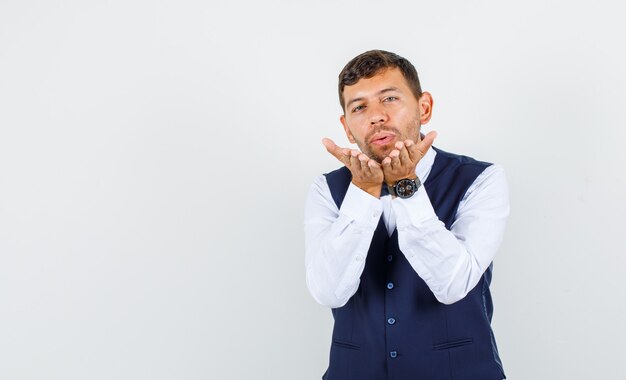 Ober stuurt kus door op handpalmen in shirt, vest te blazen en er schattig uit te zien, vooraanzicht.