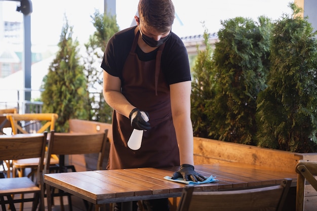 ober werkt in een restaurant in een medisch masker, handschoenen tijdens pandemie van het coronavirus