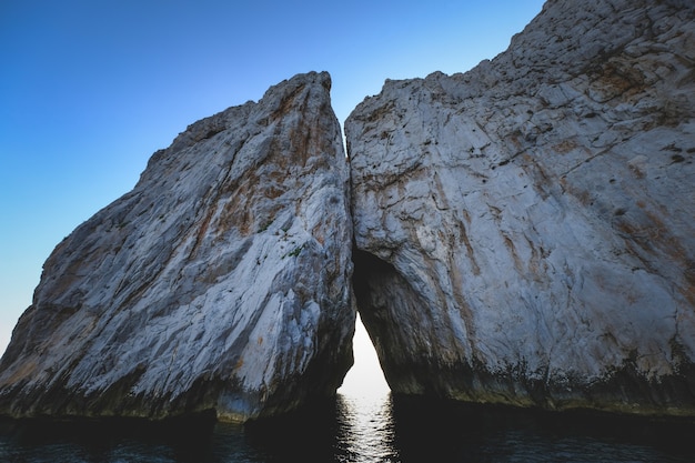 Gratis foto oceaan omringd door de rotsachtige kliffen die glinsteren onder de blauwe lucht - geweldig voor achtergronden