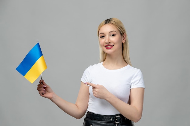 Gratis foto oekraïne russisch conflict blond schattig meisje met rode lippenstift en oekraïense vlag wijzend op vlag