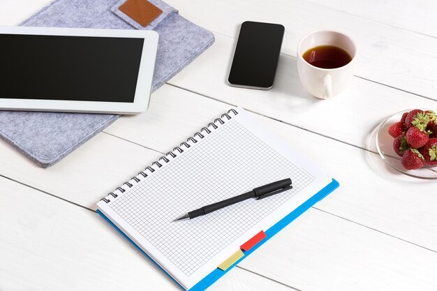 Office tafel Bureau met set van leveringen, witte lege Kladblok, beker, pen, tablet op witte achtergrond. Bovenaanzicht en kopieer ruimte voor tekst