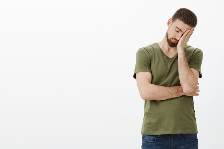 Gratis Foto oh god, hoe vervelend. portret van vermoeide en uitgeputte mannelijke workaholic met baard leunend op handpalm als gezichtspalm teken, ogen sluiten uitgeput en uitgeput poseren boos en ongemakkelijk over witte muur