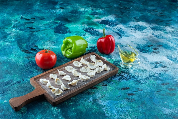 Gratis foto olie en groenten naast turkse ravioli op een bord, op de blauwe tafel.