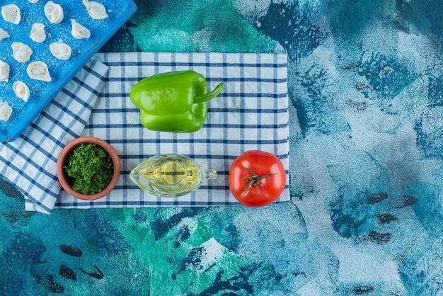 Olie en groenten naast turkse ravioli op een bord op de theedoek, op de blauwe tafel.