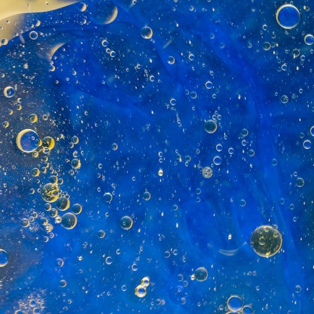 Oliebellen die op blauwe waterverfachtergrond drijven