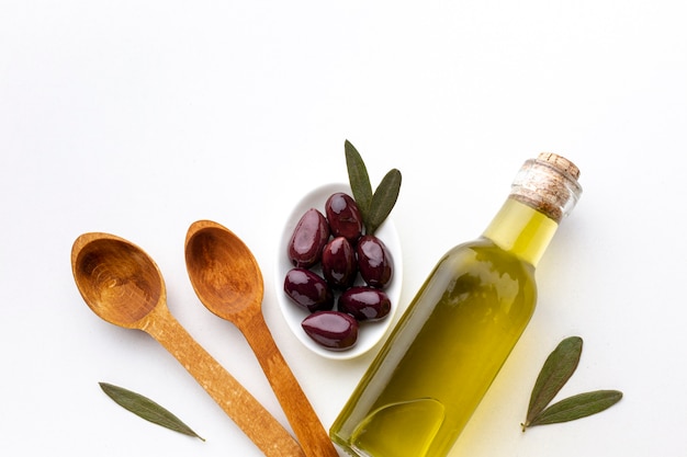Olijfoliefles paarse olijven en houten lepels