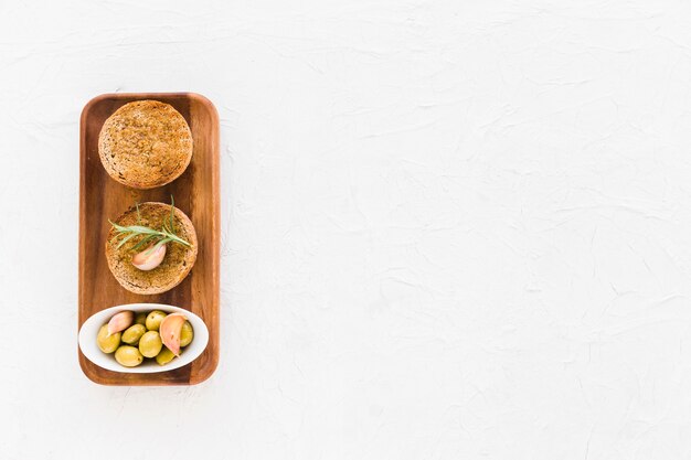 Olijven en knoflookteentjes op rond brood over de houten plank