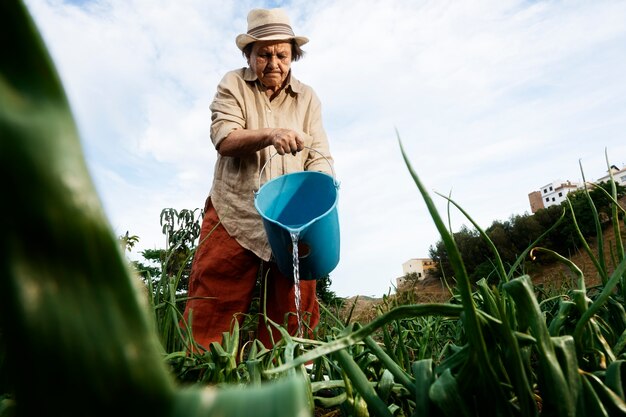 Oma geeft planten water in de tuin