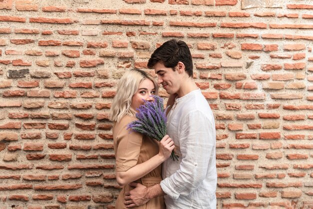 Omarmd paar poseren met boeket van lavendel