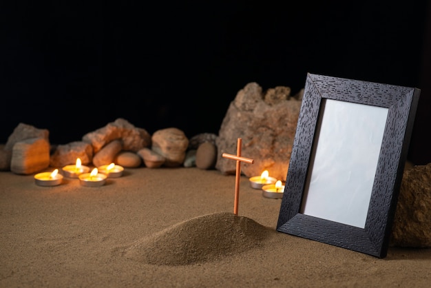Omlijsting met stenen kaarsen en klein graf op zand donker oppervlak Premium Foto