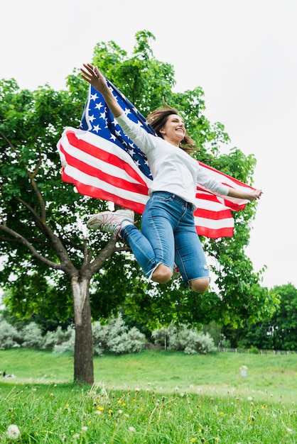 Onafhankelijkheidsdagconcept met vrouw die met Amerikaanse vlag springen