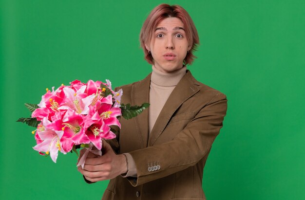 Onder de indruk jonge knappe man die een boeket bloemen uithoudt op zoek naar