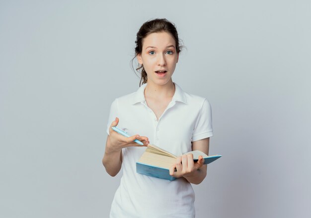 Onder de indruk jonge mooie vrouwelijke student met open boek en pen geïsoleerd op een witte achtergrond met kopie ruimte