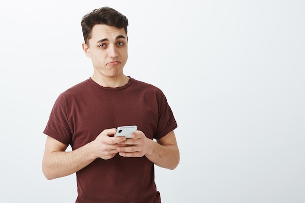 Onder de indruk knappe man in rood t-shirt met smartphone