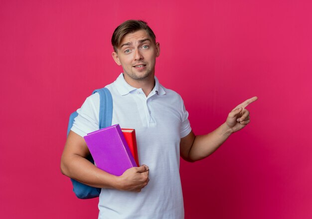 onder de indruk van jonge knappe mannelijke student die rugtas draagt die boeken en punten aan kant houdt