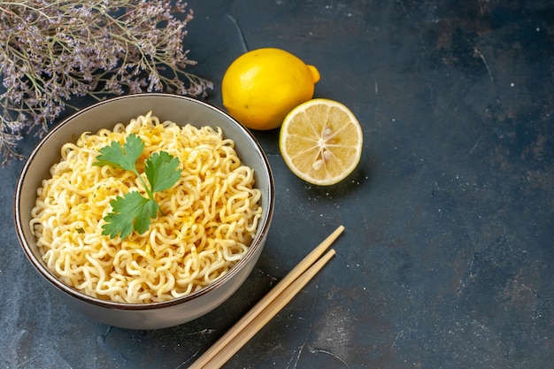 Onderaanzicht aziatische ramen noedels in kom citroen en gesneden citroen eetstokjes gedroogde bloemtak op donkere tafel vrije ruimte