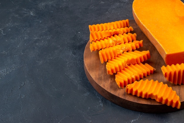 Onderaanzicht butternutpompoen gehakt met zigzagmes op een houten bord op zwarte tafelkopieplaats