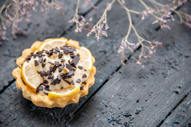 Onderaanzicht citroentaart met chocolade gedroogde bloemtak op donkere tafel