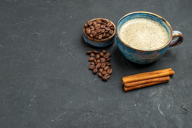 Onderaanzicht een kopje koffiekom met koffiezaden kaneelstokjes op een donkere vrije plaats