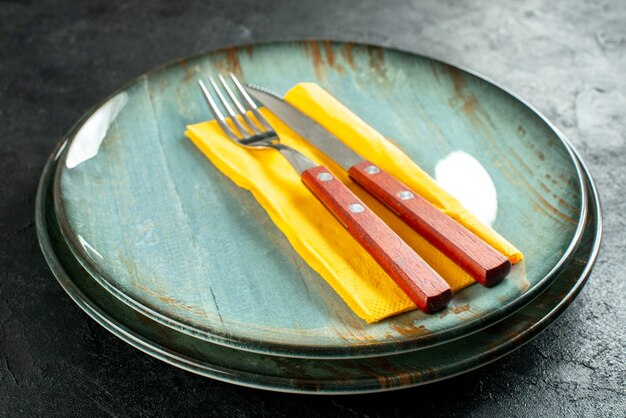 Onderaanzicht geel servetmes en vork op ronde platen op zwarte tafel