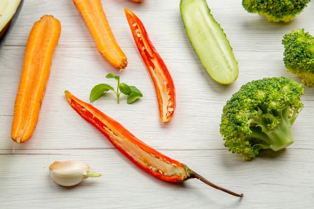 Onderaanzicht gehakte groenten komkommer broccoli wortel hete peper op grijze tafel