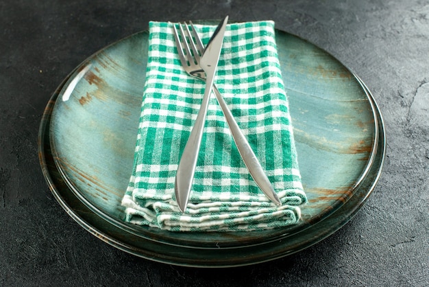 Gratis foto onderaanzicht gekruist diner mes en vork op groen en wit geruit servet op schalen op zwarte tafel