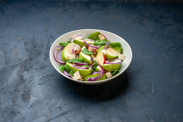 Onderaanzicht groene appelsalade in kom op donkerblauwe tafel met vrije plaats