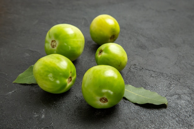 Onderaanzicht groene tomaten en laurierblaadjes op donkere achtergrond