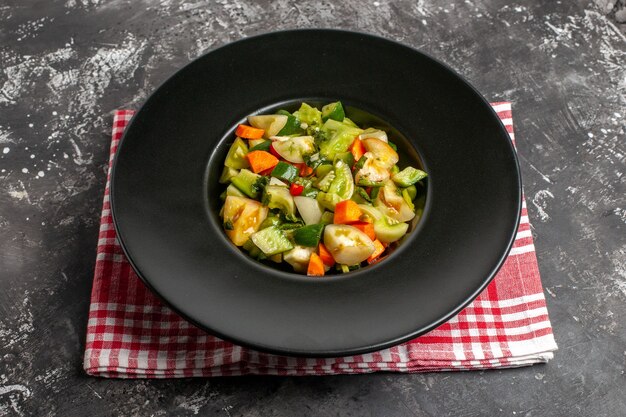 Onderaanzicht groene tomatensalade op ovale plaat op een servet op donkere achtergrond