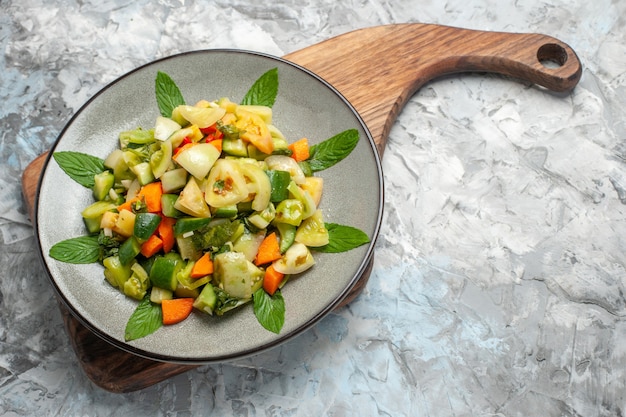 Onderaanzicht groene tomatensalade op ovale plaat op snijplank op donkere achtergrond