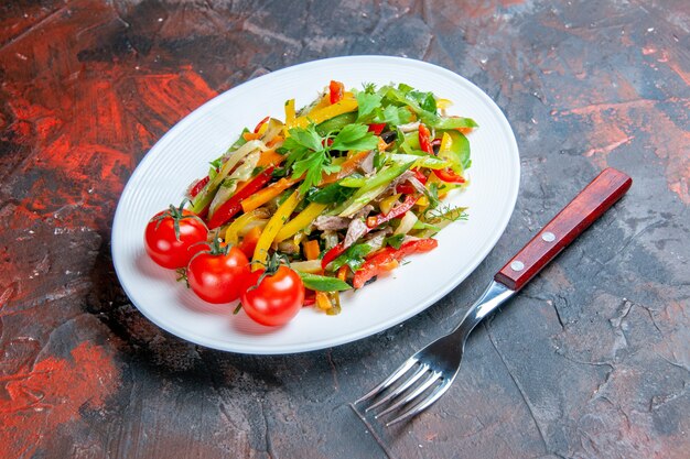 Onderaanzicht groentesalade op ovale plaatvork op donkere ondergrond