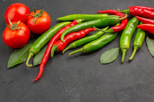 Onderaanzicht hete rode en groene paprika rode tomaten laurierblaadjes op zwarte achtergrond