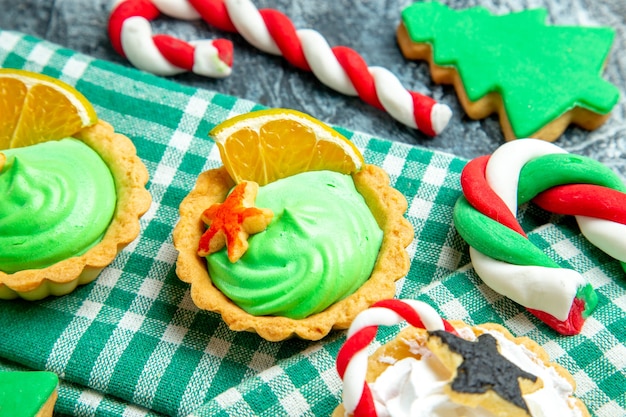 Onderaanzicht kleine kersttaartjes op tafelkleed kerstboomkoekje op grijze tafel