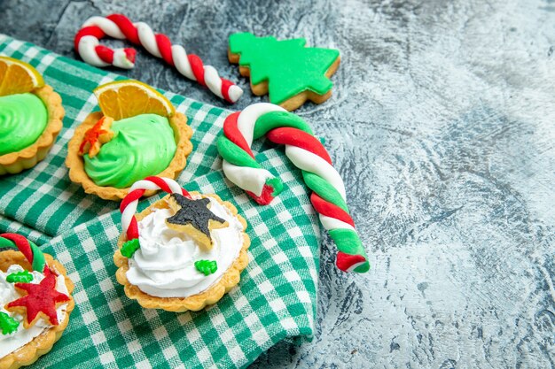 Onderaanzicht kleine kersttaartjes op tafelkleed kerstsnoepjes op grijze tafel vrije ruimte