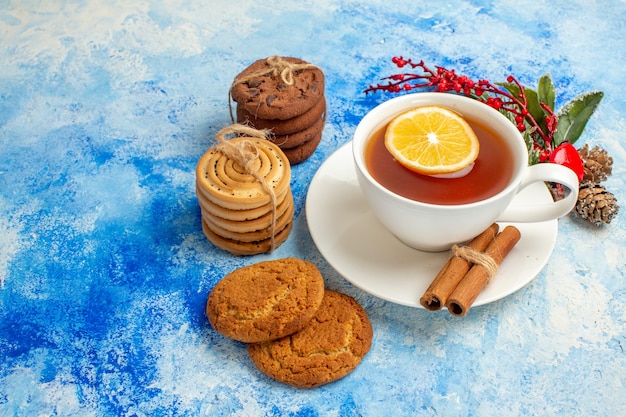 Onderaanzicht kopje thee op smaak gebracht door citroen en kaneelkoekjes vastgebonden met touw op blauwe tafel