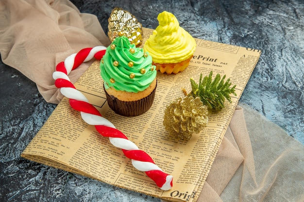 Onderaanzicht mini cupcakes xmas candy xmas ornamenten op krant beige sjaal op dark on