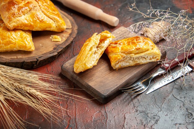 Onderaanzicht penovani khachapuri op houten bord en op snijplank mes en vork deegroller op donkerrode tafel