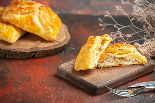 Onderaanzicht penovani khachapuri op houten bord en op snijplank mes en vork op donkerrode tafel